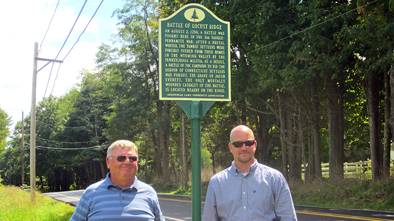 Rick Bodenschatz , left, of MATT and Eric Usbeck, general manager of the Arrowhead Lake Community Association, which sponsored the marker.