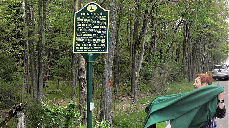 Marianne Hadjuk, president of Sullivan Trail Questers, unveils the Sullivan Bridge marker.